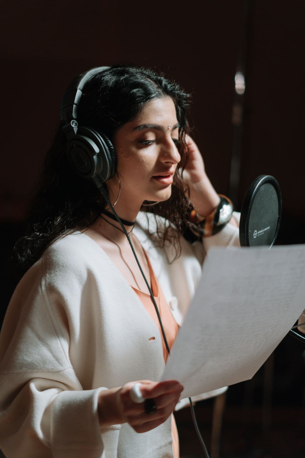Siswa vokal berlatih dengan headphone dan mikrofon di studio